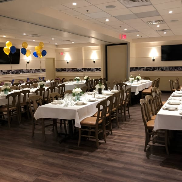 Luna Rossa's dining room set with white tablecloths, place settings, and blue and yellow balloons.