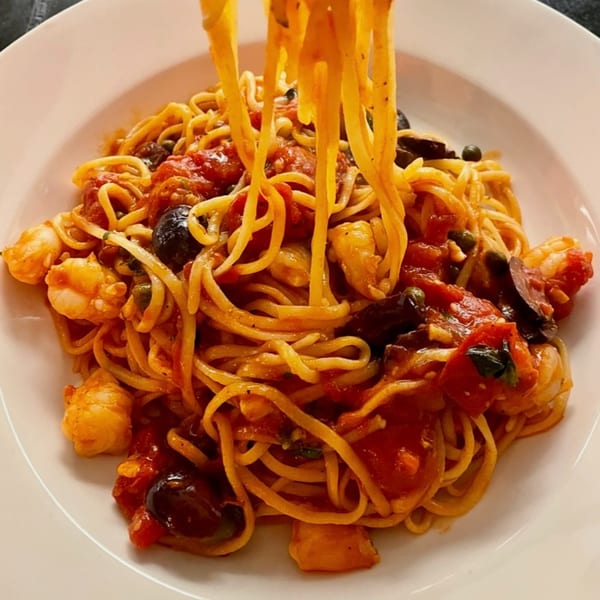 Close-up of Luna Rossa's linguine pasta with shrimp, olives, and tomato sauce being twirled.