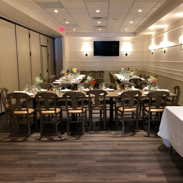 Luna Rossa's private dining room with multiple long tables set for guests, featuring wooden chairs and floral centerpieces.